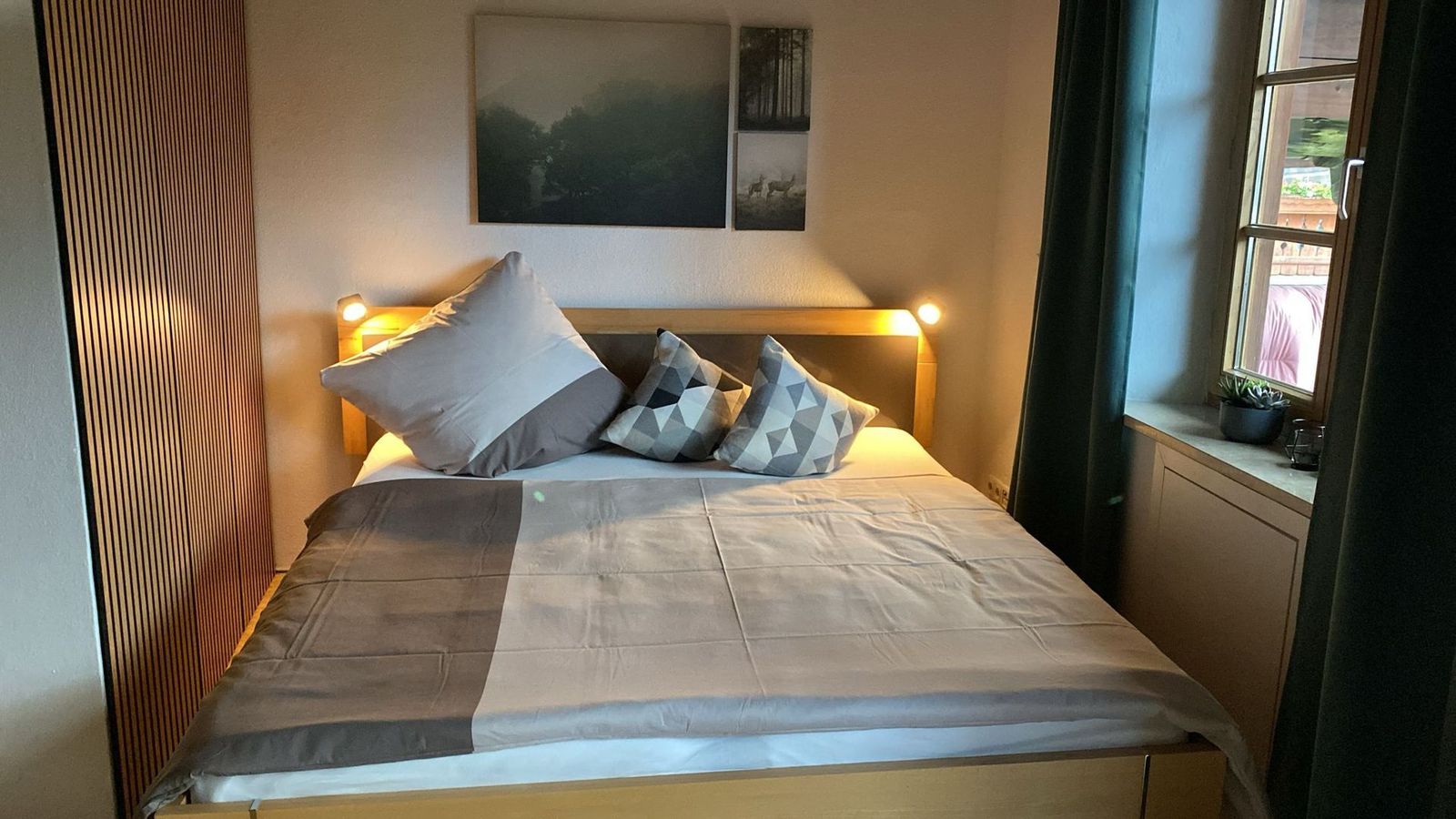 Schlafzimmer der Ferienwohnung Bergblick mit Doppelbett, Holzverkleidung und Leseleuchten