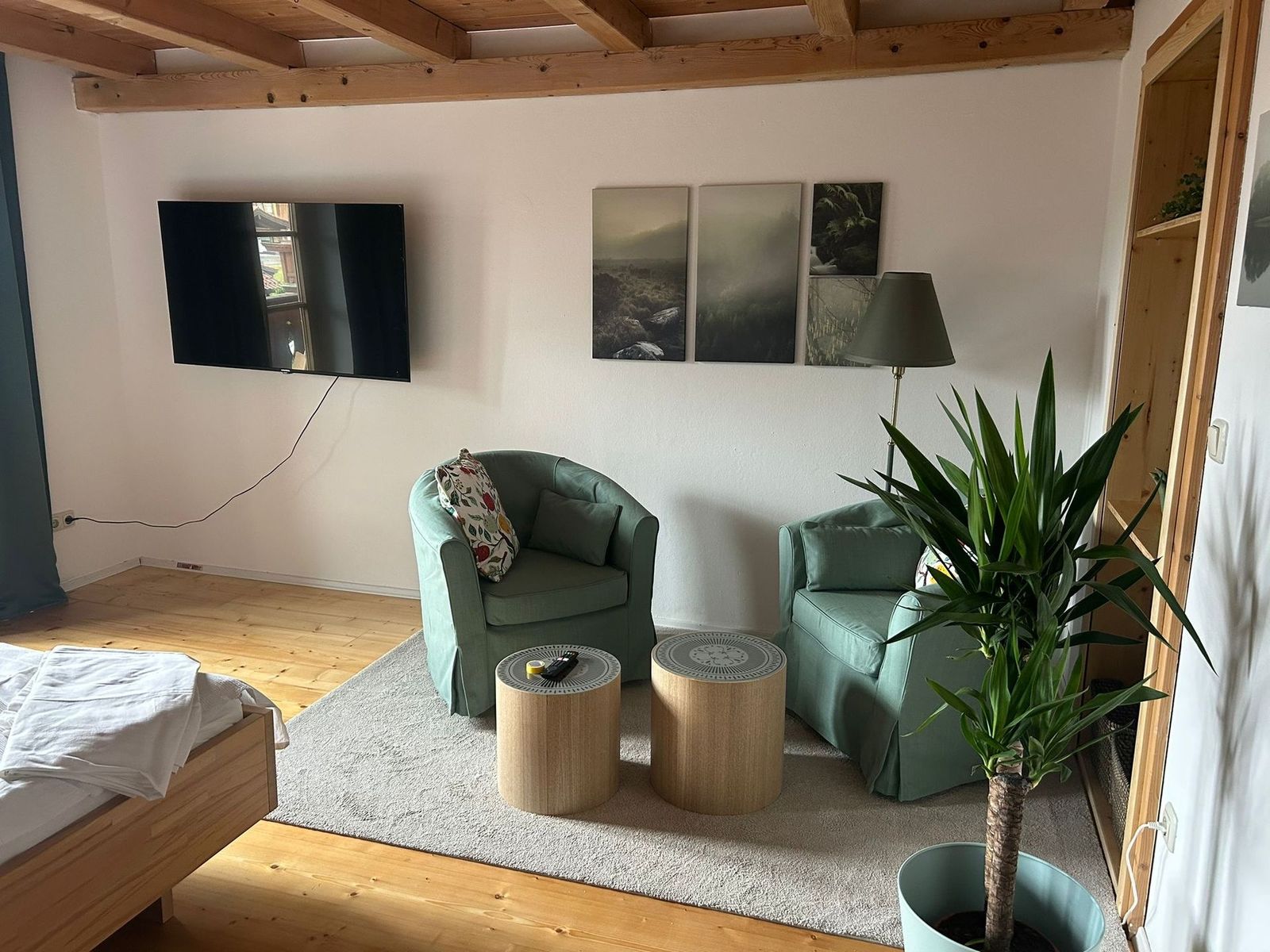 Wohnbereich der Ferienwohnung Bergblick mit Sesseln, Fernseher und Bildern an der Wand