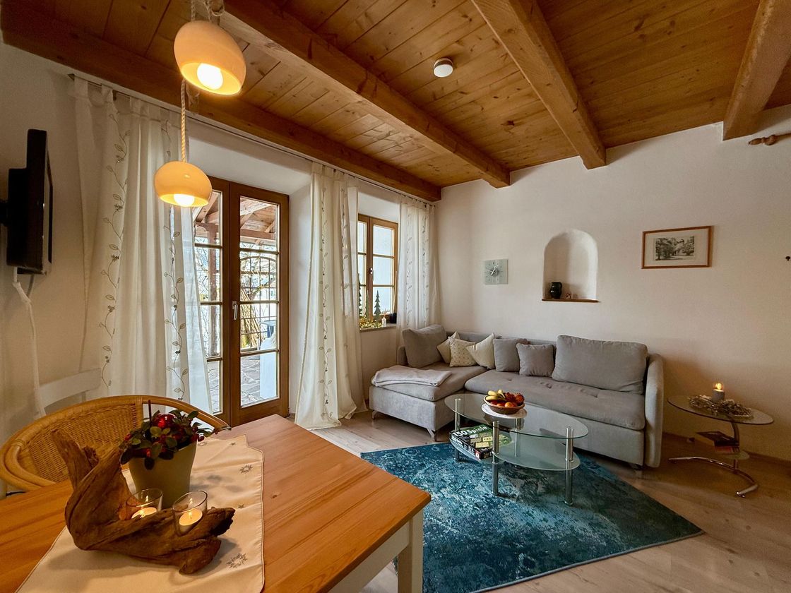 Wohnbereich der Ferienwohnung Sonnengarten mit Sofa, Esstisch und Zugang zur privaten Terrasse